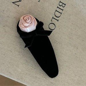 Détail d'une pince à cheveux rose en satin avec base en velours noir et un nœud