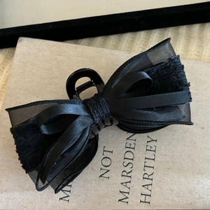 Close-up of elegant black layered silk and mesh bow claw clip on a vintage book