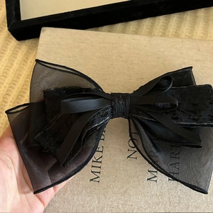 Close-up of elegant black layered mesh bow hair clip with textured fabric finish