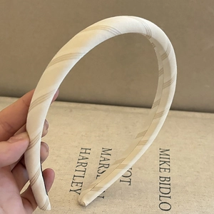 Close-up of padded cream fabric headband with brown diagonal stripe pattern