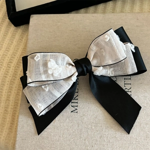 Detail of elegant black and white silk bow hair clip with polka dot mesh texture