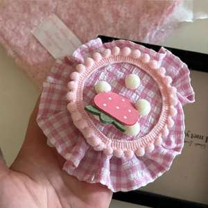 Détail d'une pince à cheveux rose à carreaux avec motif fraise et pompons blancs