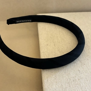 Detail view of handmade padded black headband showing twill fabric texture and label