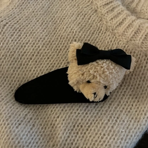 Barrette à cheveux ours en peluche avec nœud noir sur fond de pull en maille beige
