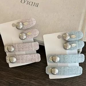Macro shot of tweed fabric hair clips with gray pearls and golden charms on display
