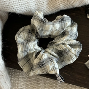 Classic black and white plaid seersucker hair scrunchie on a wooden surface with a sweater