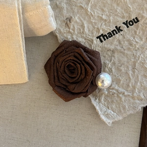 Elegant maple brown fabric rose hair clip with a pearl accent on a vintage background