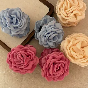 Detailed view of handmade chiffon rose flower hair ties in blue, peach, and pink colors