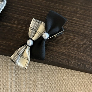 Close-up of black and white plaid bow hair clip with pearls and metal alligator base