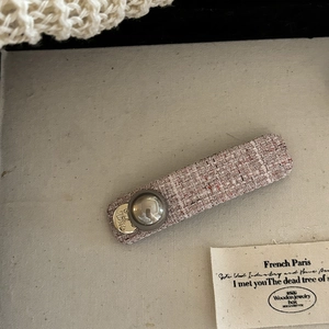 Detail view of retro pink tweed hair clip with grey button and golden metal pendant
