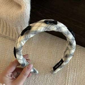 Detail of a wide plaid headband with small black satin bows and handmade inner label