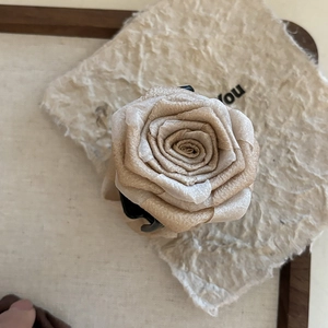Detailed view of maple brown fabric flower hair claw clip on vintage wooden tray backdrop