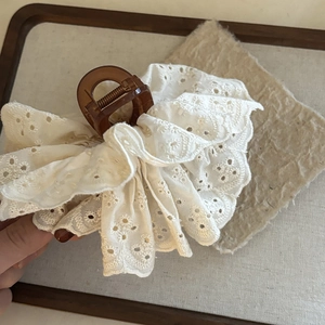 Detailed close-up of French lace embroidery texture on a large brown hair claw clip