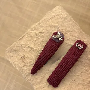 Detailed macro view of burgundy corduroy hair clips with silver butterfly and pink gemstone