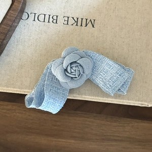 Elegant blue tweed camellia flower hair clip with a stylish bow on beige fabric