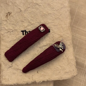 Detailed view of burgundy butterfly and rhinestone hair clips with textured fabric wrap