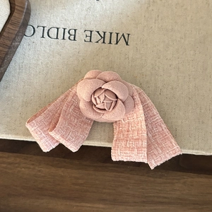 Detail view of pink camellia hair clip with elegant tweed fabric bow on textured box