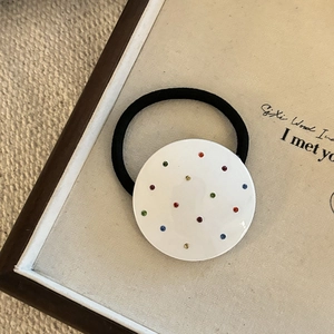 Nahaufnahme der weißen runden Haarklammer mit bunten Strasssteinen und schwarzem Gummiband