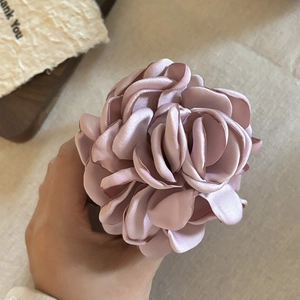 Detailed close-up of a large pink satin rose hair claw clip with elegant silk texture