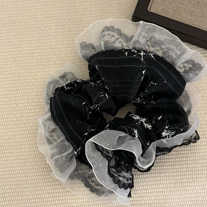 Detail of elegant black and white lace scrunchie with layered organza and floral patterns