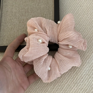 Dettaglio dell'elastico per capelli rosa plissettato con perle bianche e tessuto
