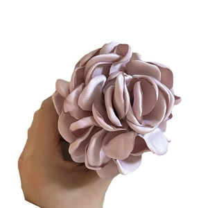 Large pink satin rose hair claw clip for French style updos held in hand by a model