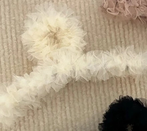Vue détaillée de grandes pinces à cheveux en dentelle beige et rose pour coiffure