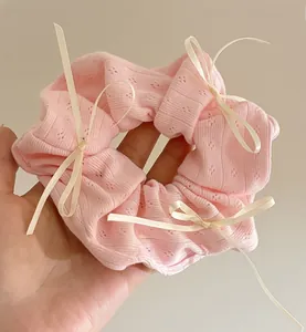 Gros plan sur chouchou en maille rose avec texture côtelée et petits nœuds en satin