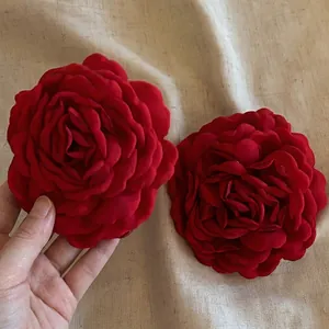 Elegante set van twee grote rode stoffen rozen haarklemmen op beige linnen achtergrond