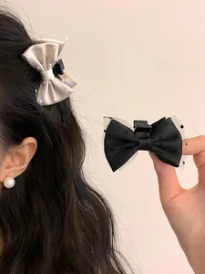 Detailed view of the black and beige bow hair clips with polka dot mesh and satin finish