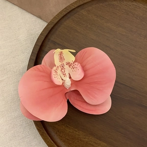 Realistic coral pink phalaenopsis orchid hair clip on wood plate for beach vacation