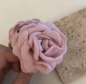 Gedetailleerde close-up van de gelaagde lichtroze chiffon bloem haarklem decoratie