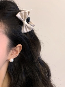 Close-up of beige bow hair clip with polka dot mesh on model wearing pearl earring