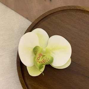 Detailed close-up of a realistic orchid hair clip on a wooden tray with warm lighting