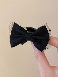 Close-up of black bow hair claw clip featuring delicate mesh overlay and satin fabric texture