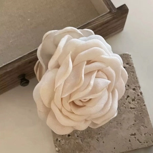 Elegante crème stoffen rozen haarklem voor dames op een gestructureerd stenen oppervlak