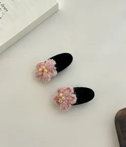 Vue détaillée de deux pinces à cheveux fleurs de cerisier roses en tricot et perles
