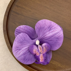 Macro detail of purple orchid hair clip showing realistic petals and texture