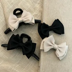 Detail view of a 4-piece set featuring elegant black and cream satin bow hair claw clips