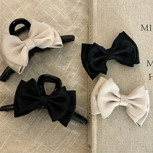 Elegant satin double bow hair claws in black and champagne gold on vintage book background
