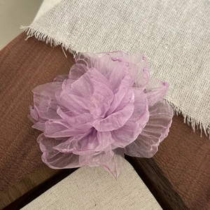 Close-up of a purple floral hair clip with delicate mesh petals in a vintage setting