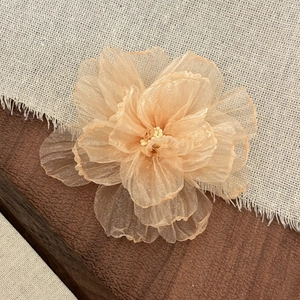 Macro shot of layered organza flower hair clip with champagne petals and pearl stamen