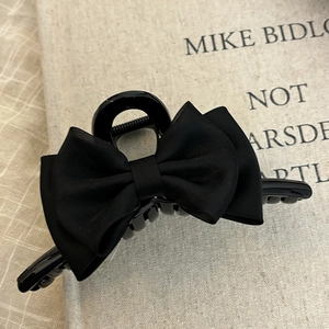 Detail of elegant black double-layered bow hair claw clip with matte silk texture finish