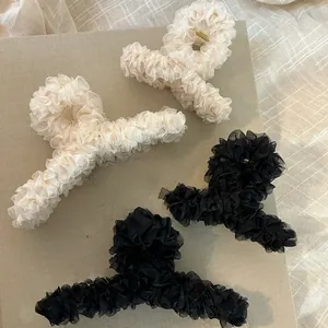 Dettagli di eleganti mollette per capelli in organza a pieghe in crema e nero per acconciature
