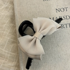 Detailed view of a champagne satin bow hair claw clip on a stylish decorative background