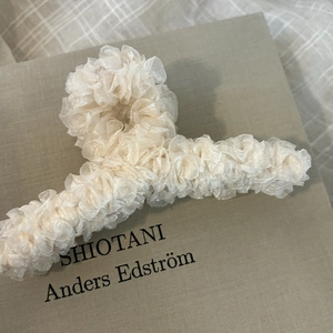 Vista dettagliata del fermaglio per capelli in chiffon crema con trama a pieghe eleganti