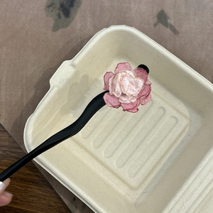 Close-up of a handmade pink floral wooden hair stick with a wavy black matte stem