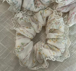 Détail de chouchou floral avec bordure en dentelle beige et motifs violets et jaunes