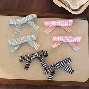 Detail view of plaid fabric bow hair clips in pink, blue, and black check patterns