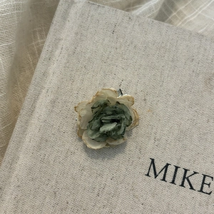 Detailed close-up of a vintage fabric flower hair pin on a textured decorative book